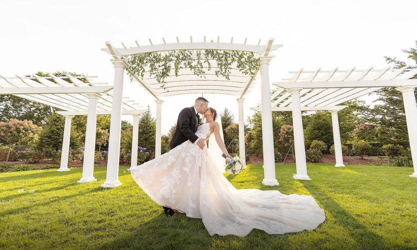 Ocean Edge Bride and Groom kissing in front of the pergola, Front Lawn wedding at Ocean Edge