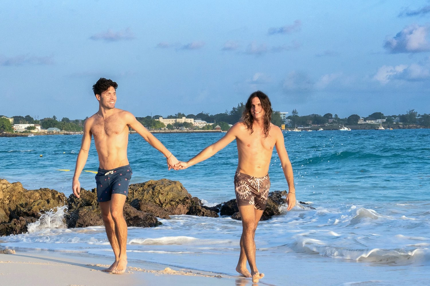 two men holding hands on a beach