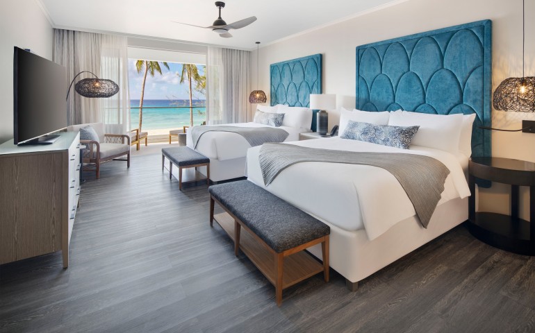 2 queen beds with blue headboards and view of ocean
