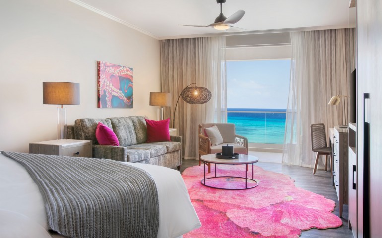 living room of suite with pink carpet and view of ocean