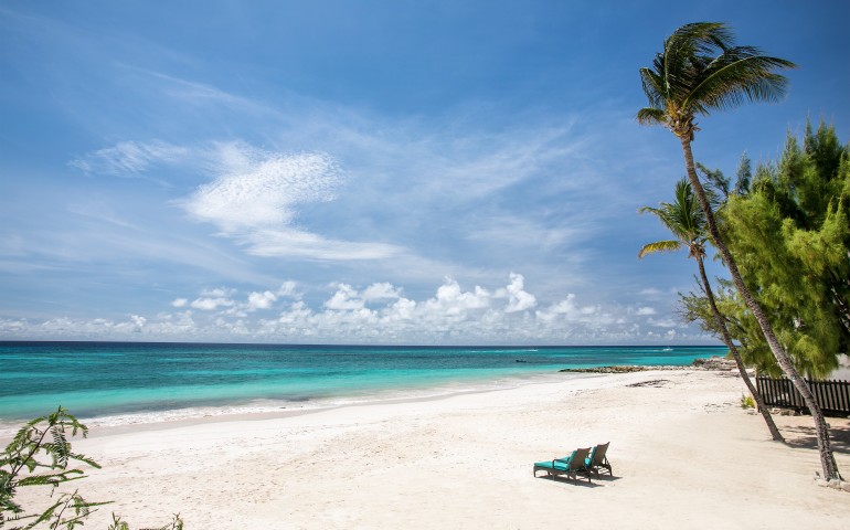 wide beach shot of 2 lounge chairs and ocean