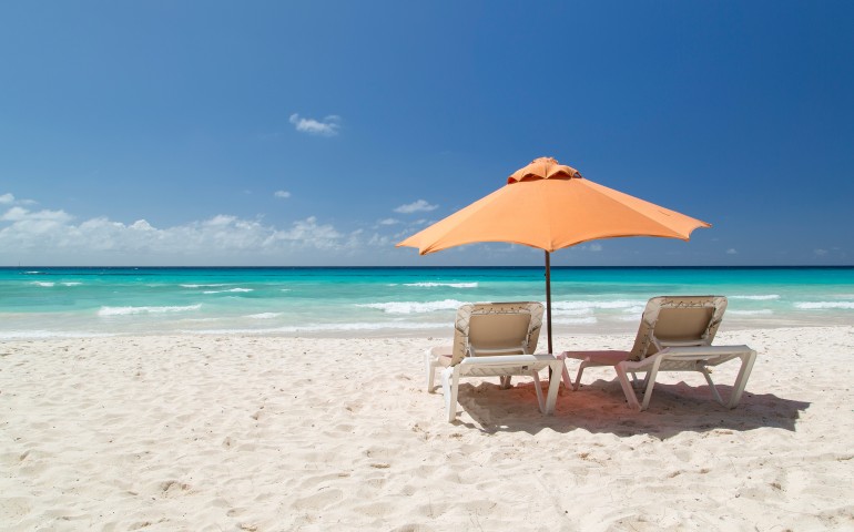 beachfront area with lounge area and orange umbrella