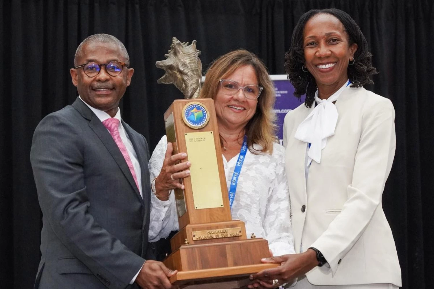 Three happy people holding an award