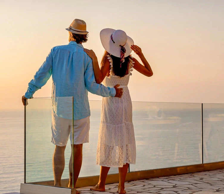 couple standing on balcony looking at ocean
