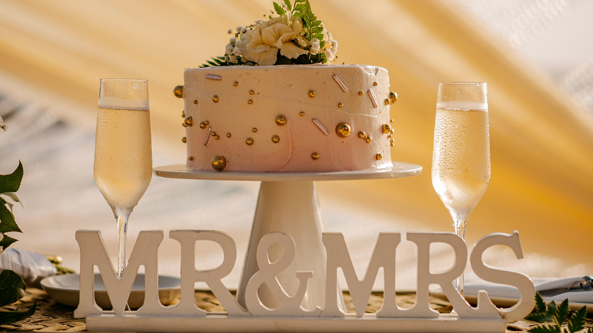 a cake on a stand next to glasses of champagne
