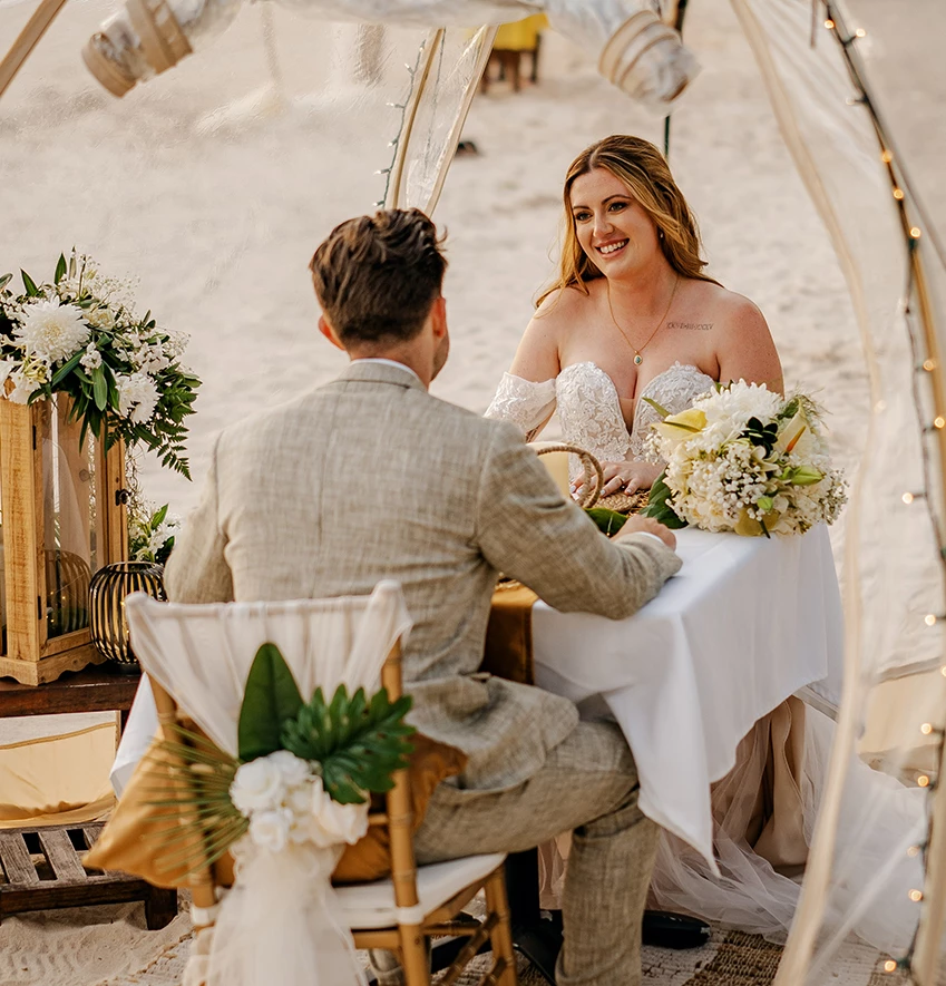 a man and woman sitting at a table with flowers