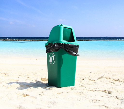 a green trash can on a beach