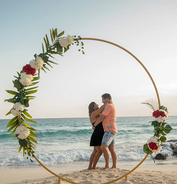 couple with arms around each other behind a circle with flowers