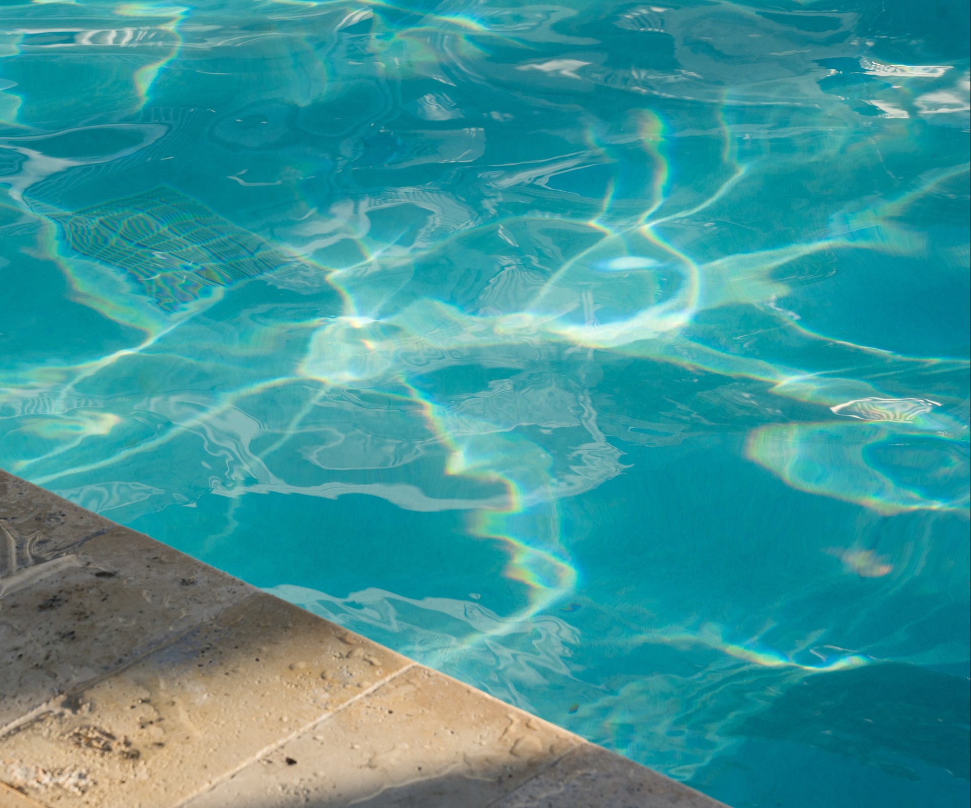 a pool with blue water and sunlight reflecting on the surface