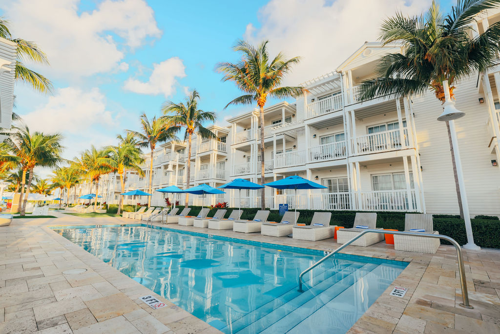 a pool with chairs and umbrellas in front of a building