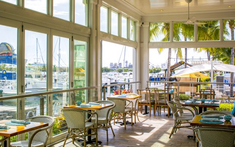 a room with tables and chairs and a view of the marina