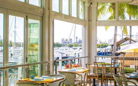 a room with tables and chairs and a view of the water from the deck