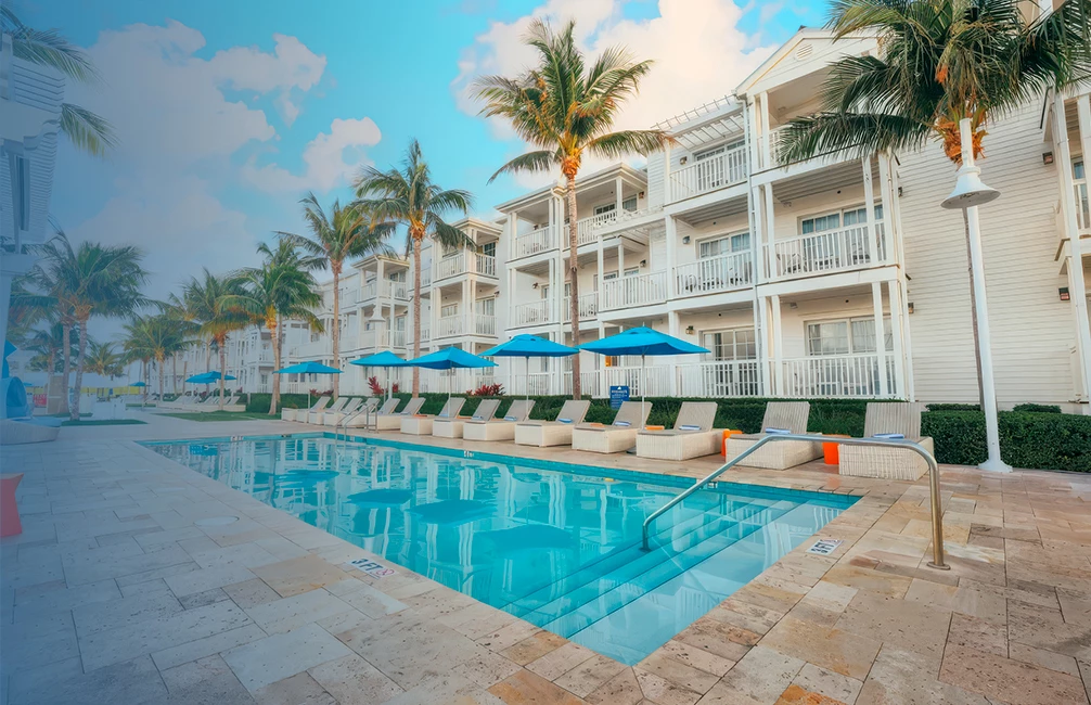 a pool with blue umbrellas and palm trees
