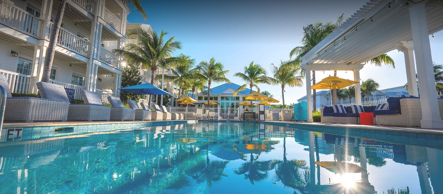 a pool with chairs and umbrellas by a building