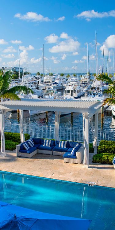 a pool with a couch and a large body of water with boats in the background