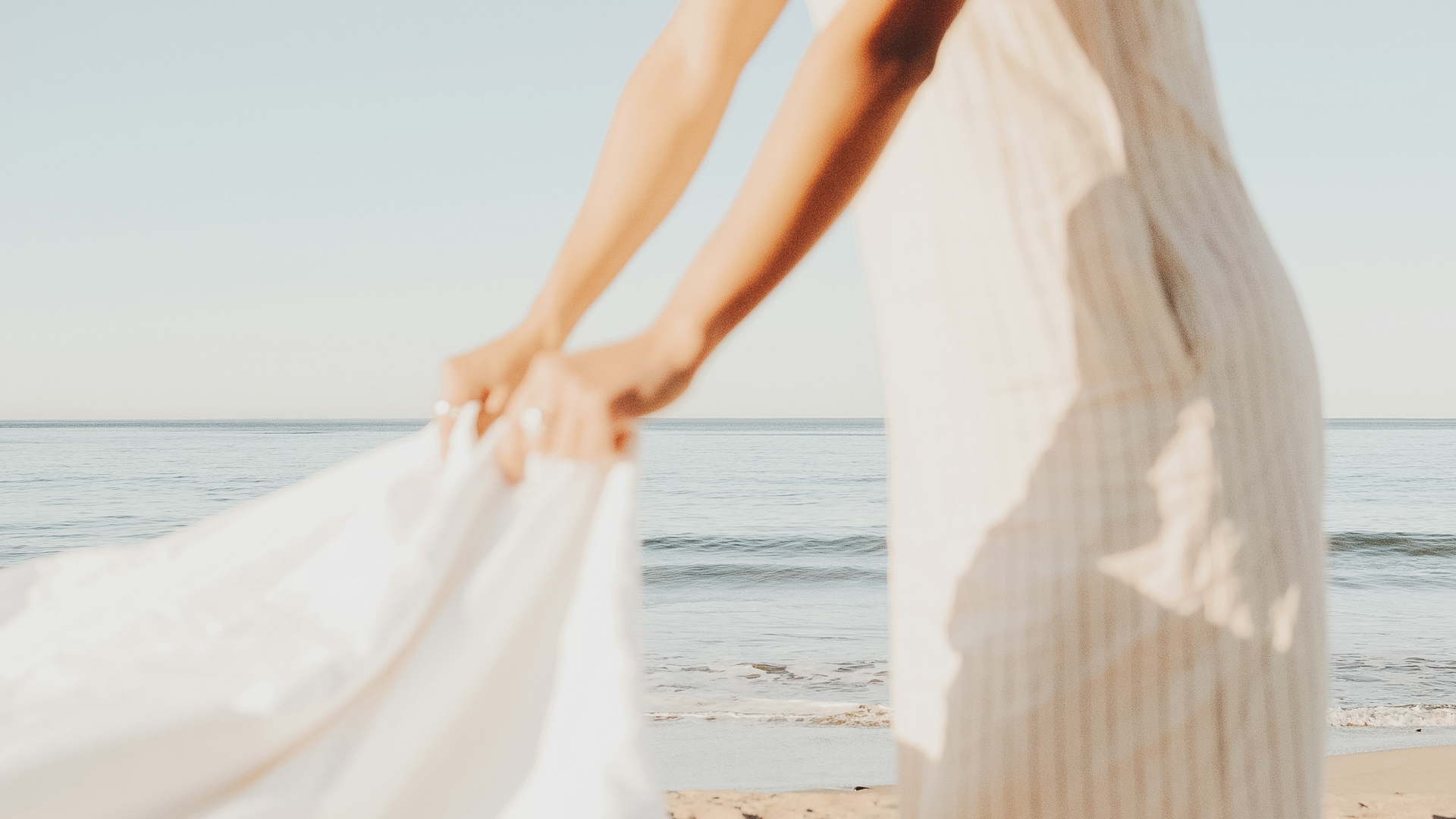 a person holding a white dress on a beach