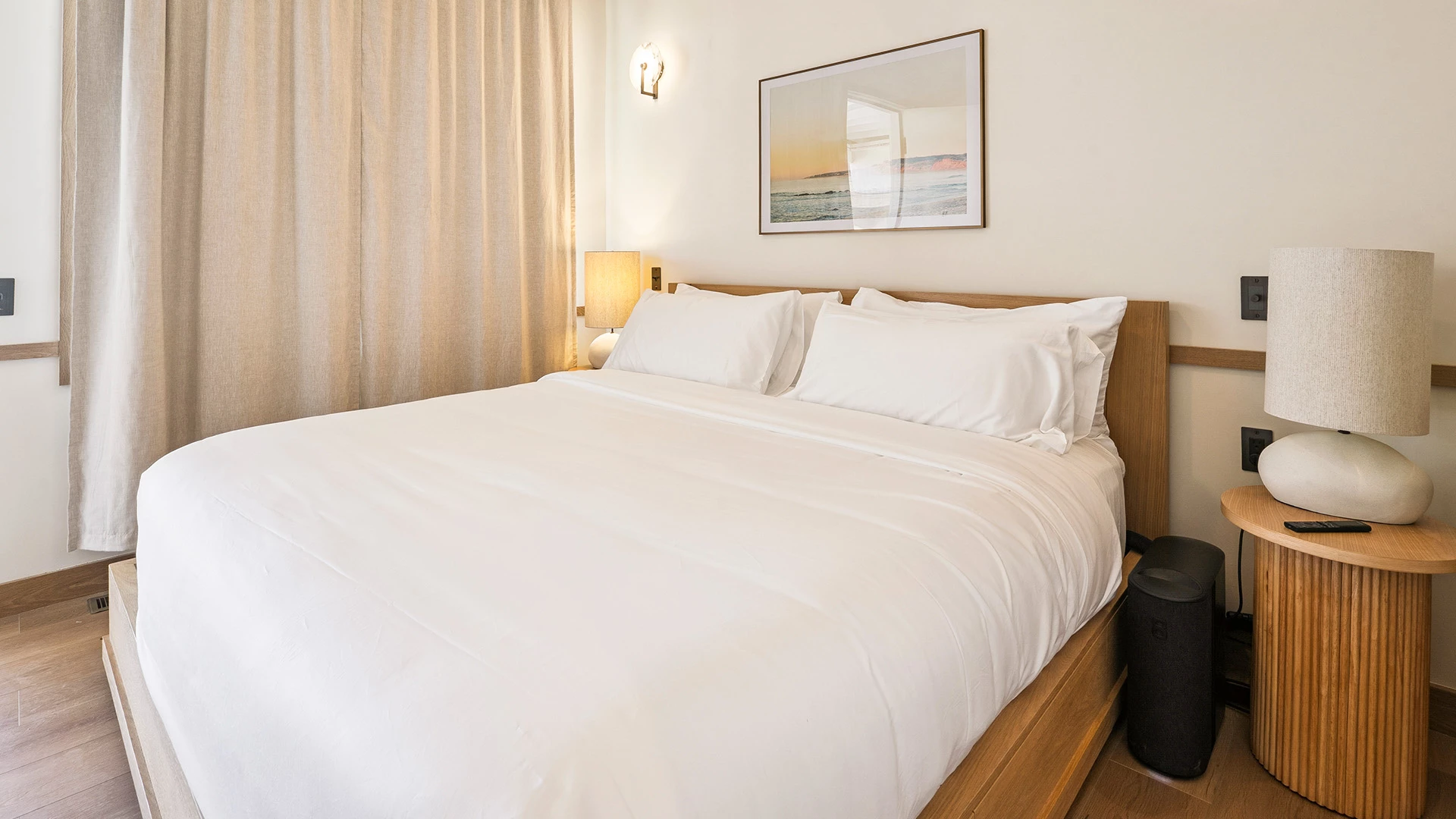 a bed with white sheets and a picture on the wall