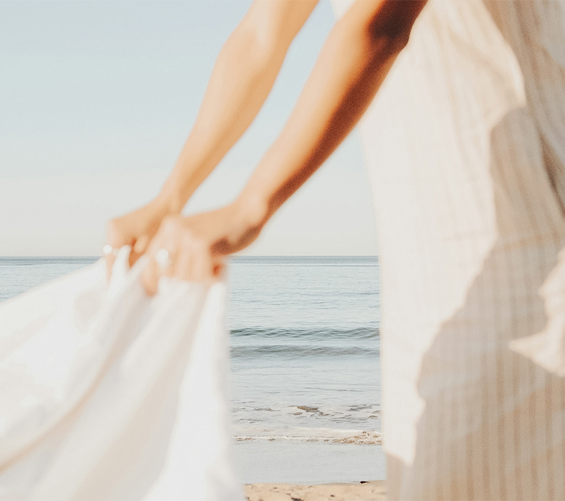 a person holding a white dress on a beach