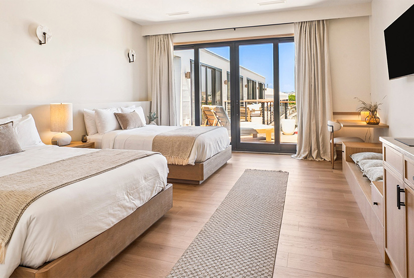 a room with two beds and a door to a deck