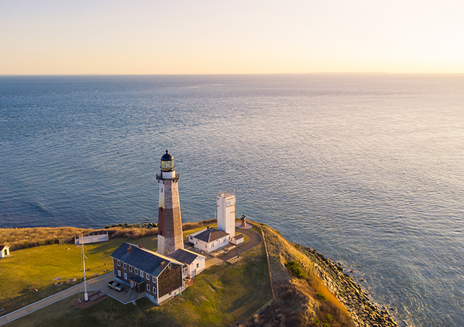 a lighthouse on a hill with a body of water in the background