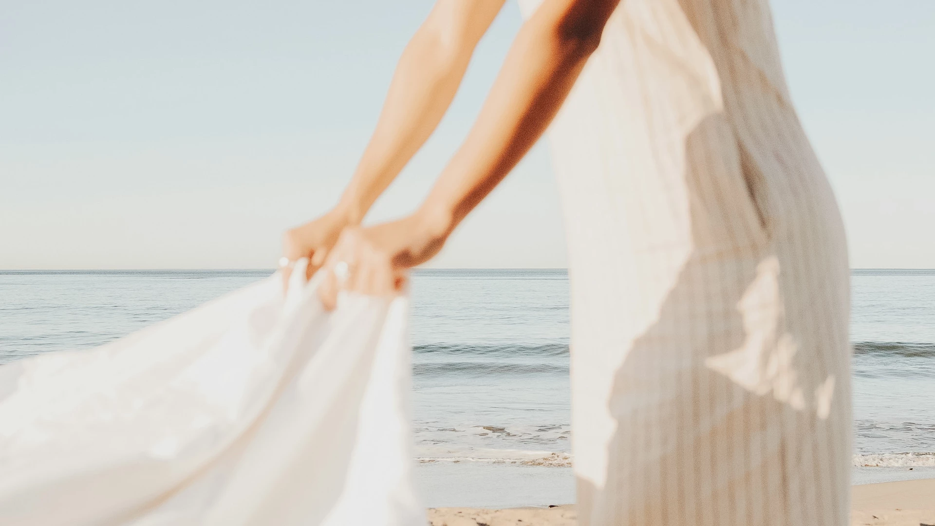 a woman holding a white dress on a beach