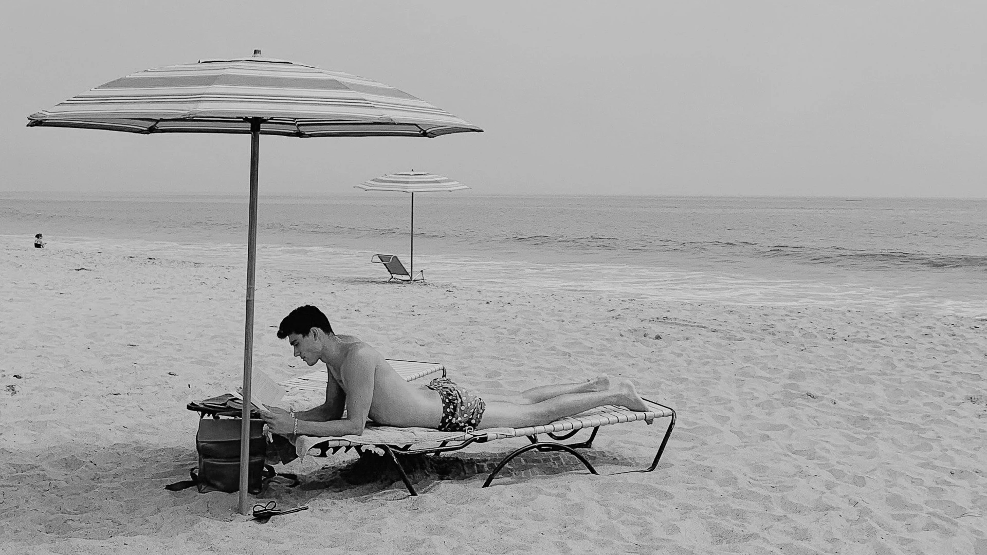 a man lying on a chair on a beach reading a book