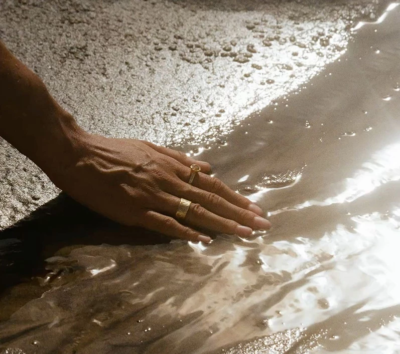 a hand touching wet sand