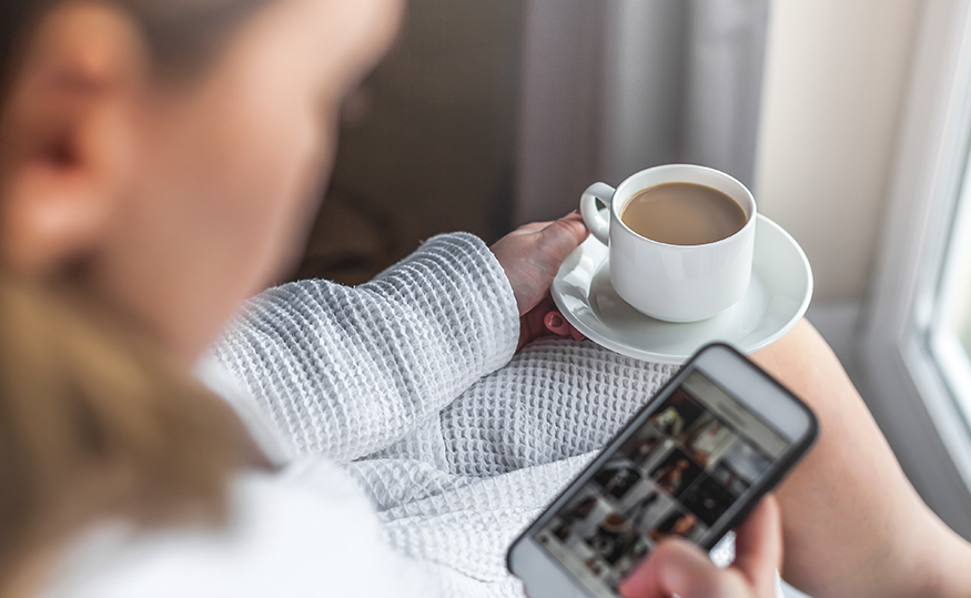 a person holding a phone and a cup of coffee