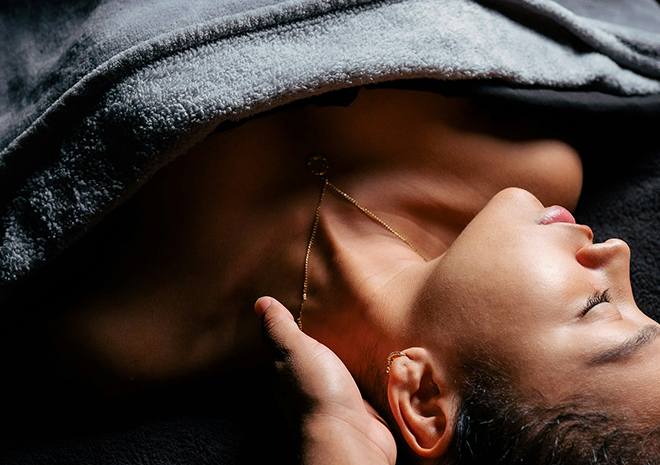 a woman lying down with a necklace on her neck