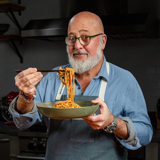 a man holding a bowl of noodles