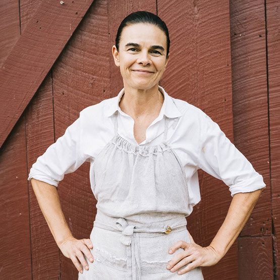 a woman standing in front of a red barn