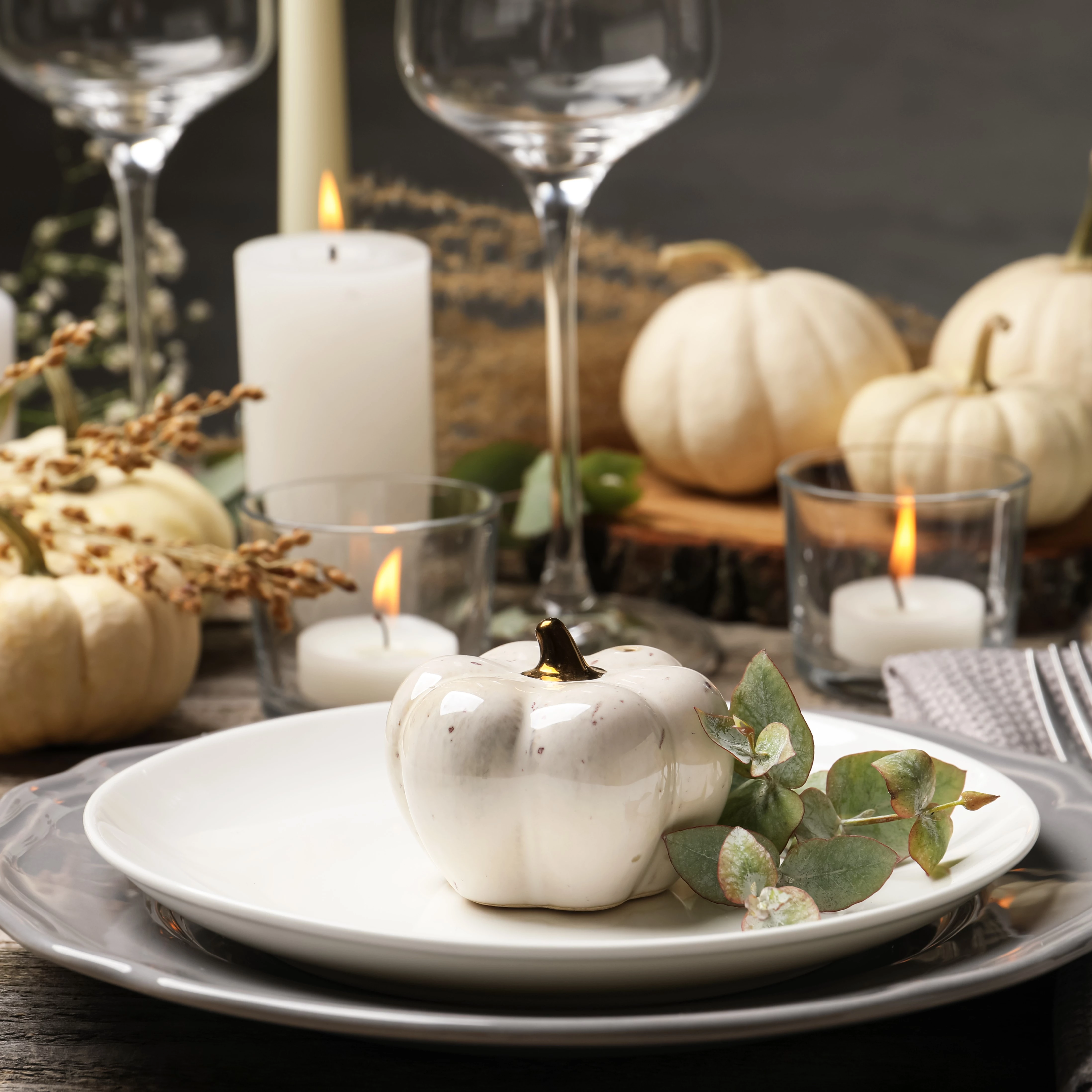 a table setting with white pumpkins and candles