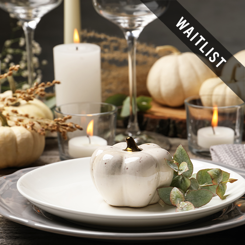 a white pumpkin on a plate with candles and glasses