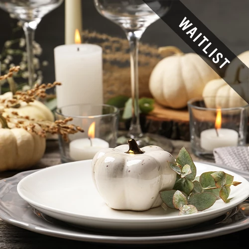 a white pumpkin on a plate with candles and glasses
