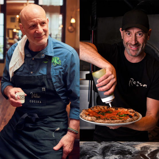 a man in a black hat and apron holding a pizza