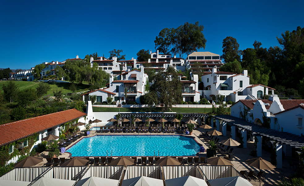 a pool with chairs and umbrellas in front of buildings