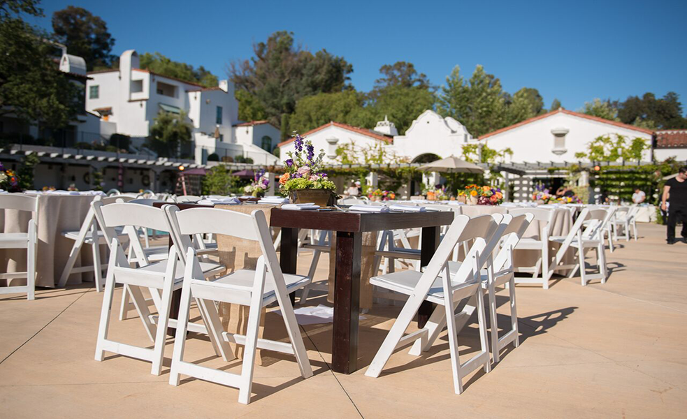 a table and chairs outside with white chairs