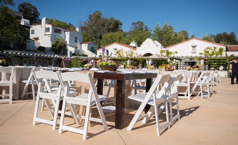 a table and chairs outside with white chairs