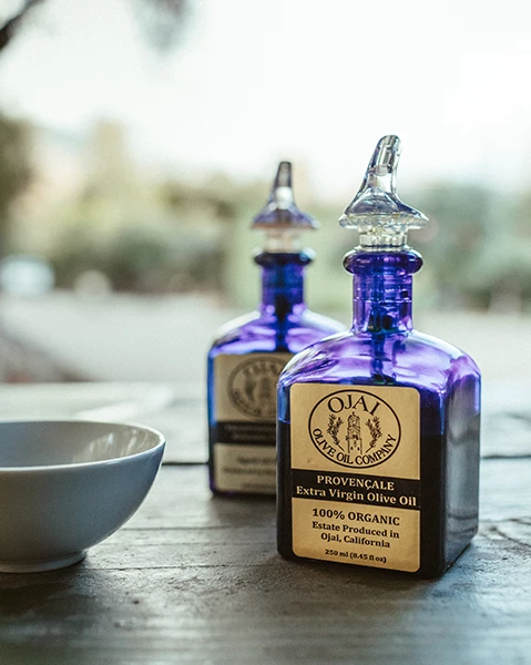 two bottles of oil next to a bowl