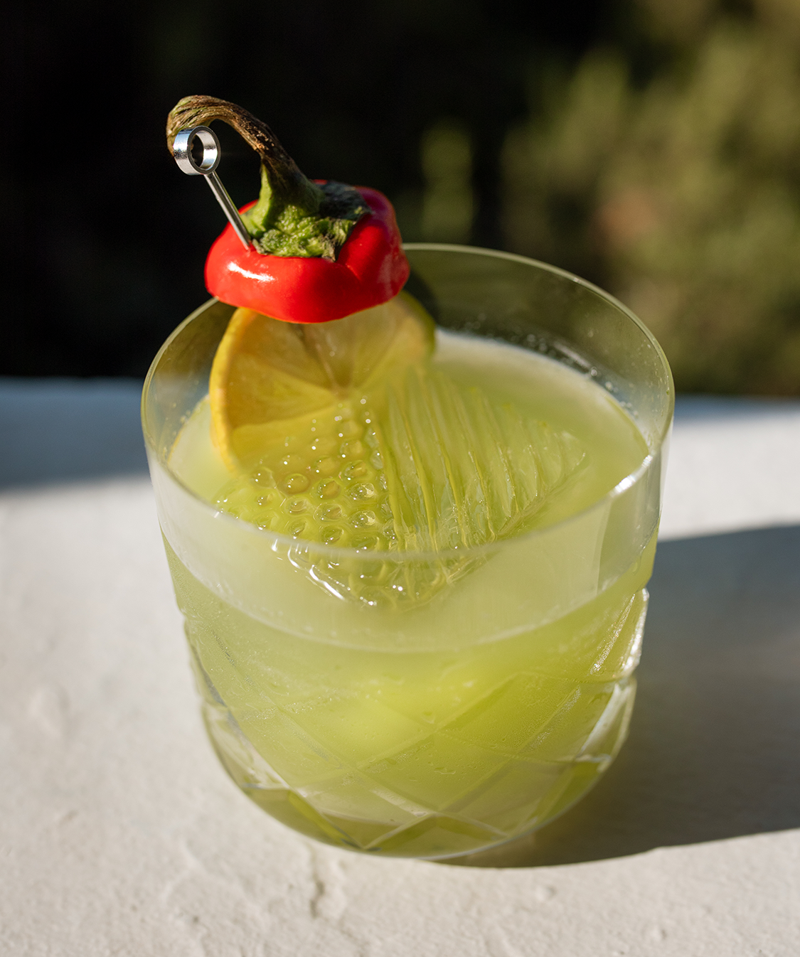 a glass with a drink and a pepper on top