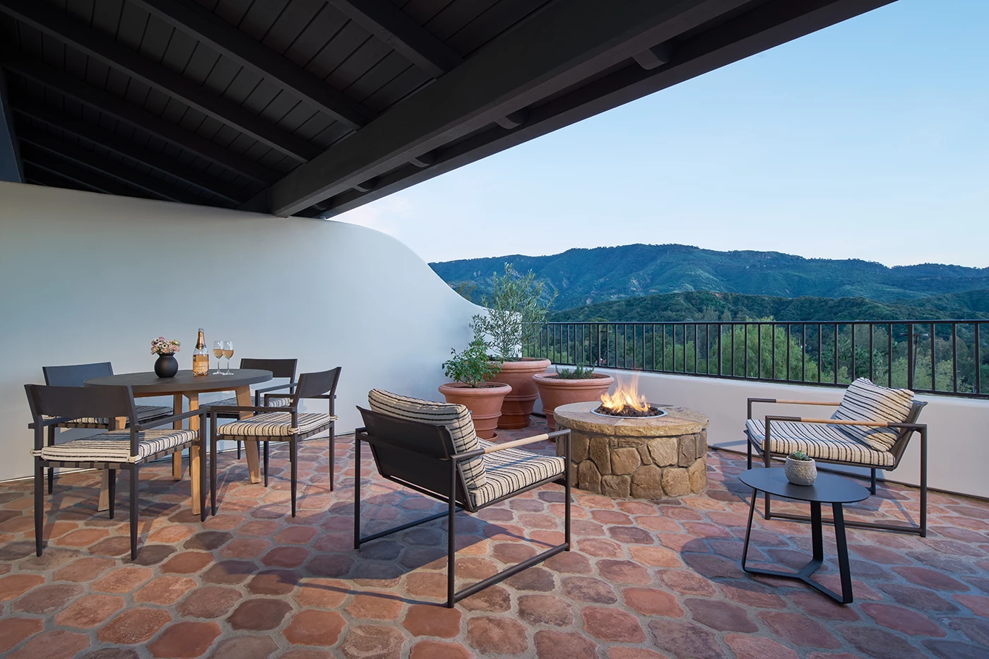 a patio with a fire pit and chairs
