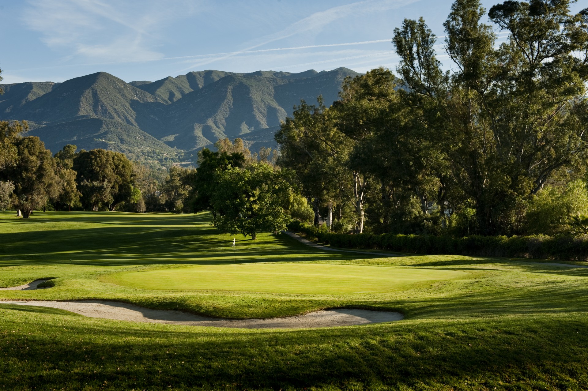 a golf course with trees and mountains in the background