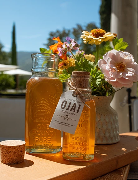 a bottle of honey and a vase of flowers
