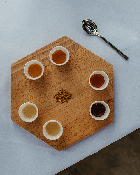 a wooden board with small cups of liquid and a spoon