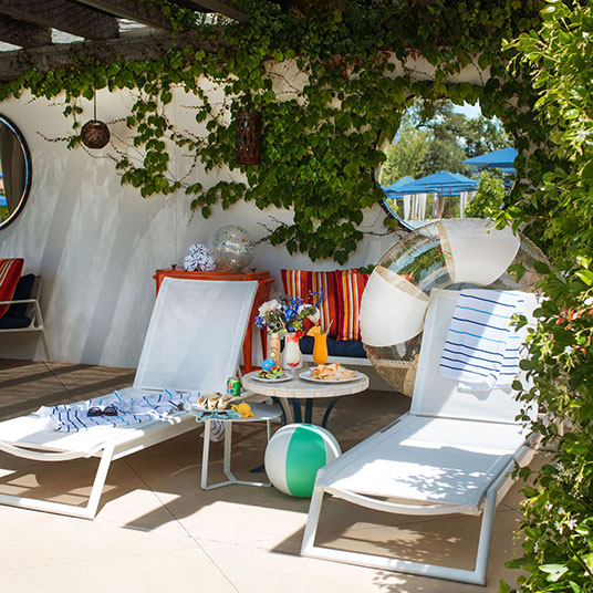 a pool with umbrellas and chairs next to a building with trees in the background