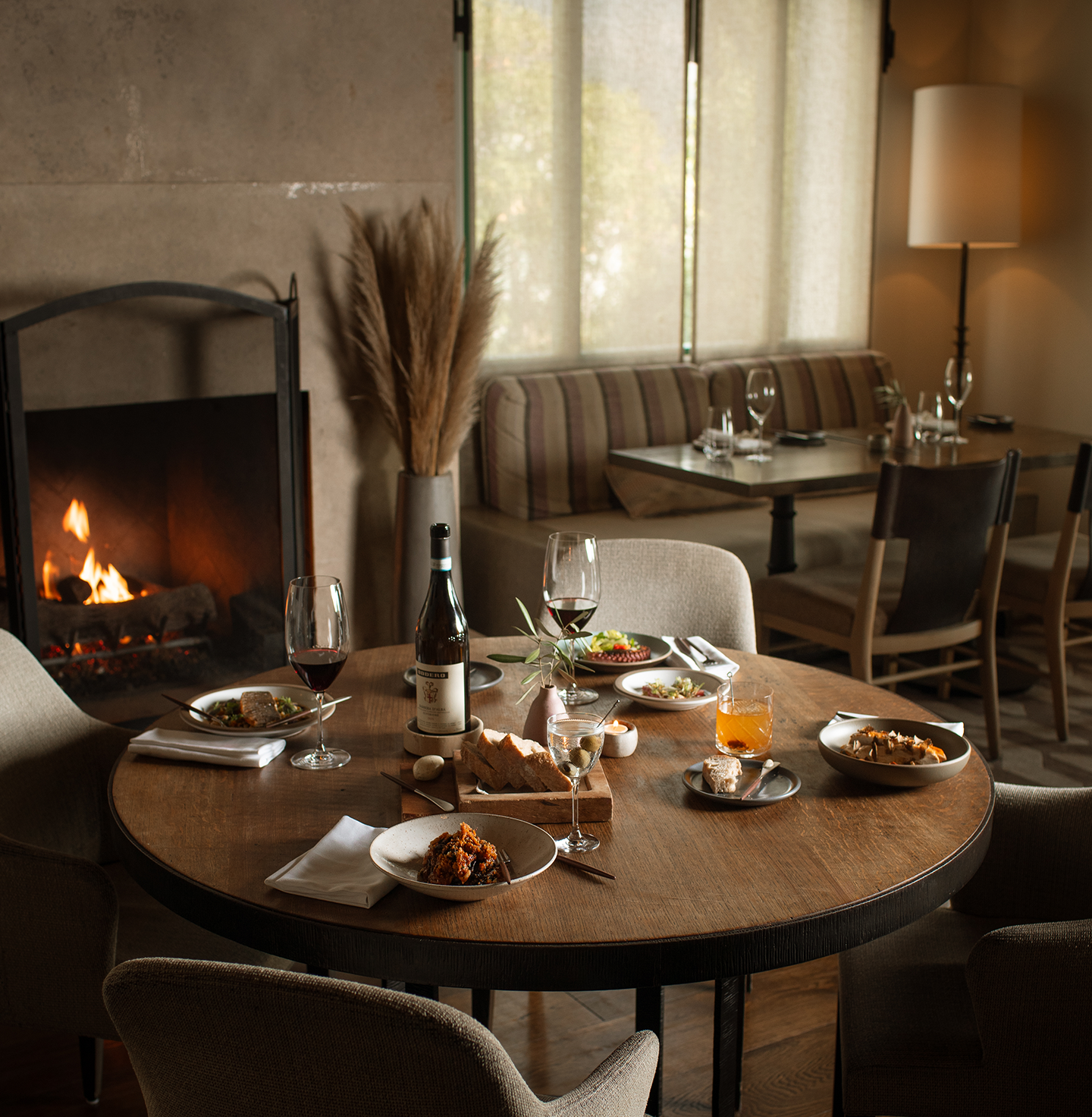a table with food and wine in front of a fireplace