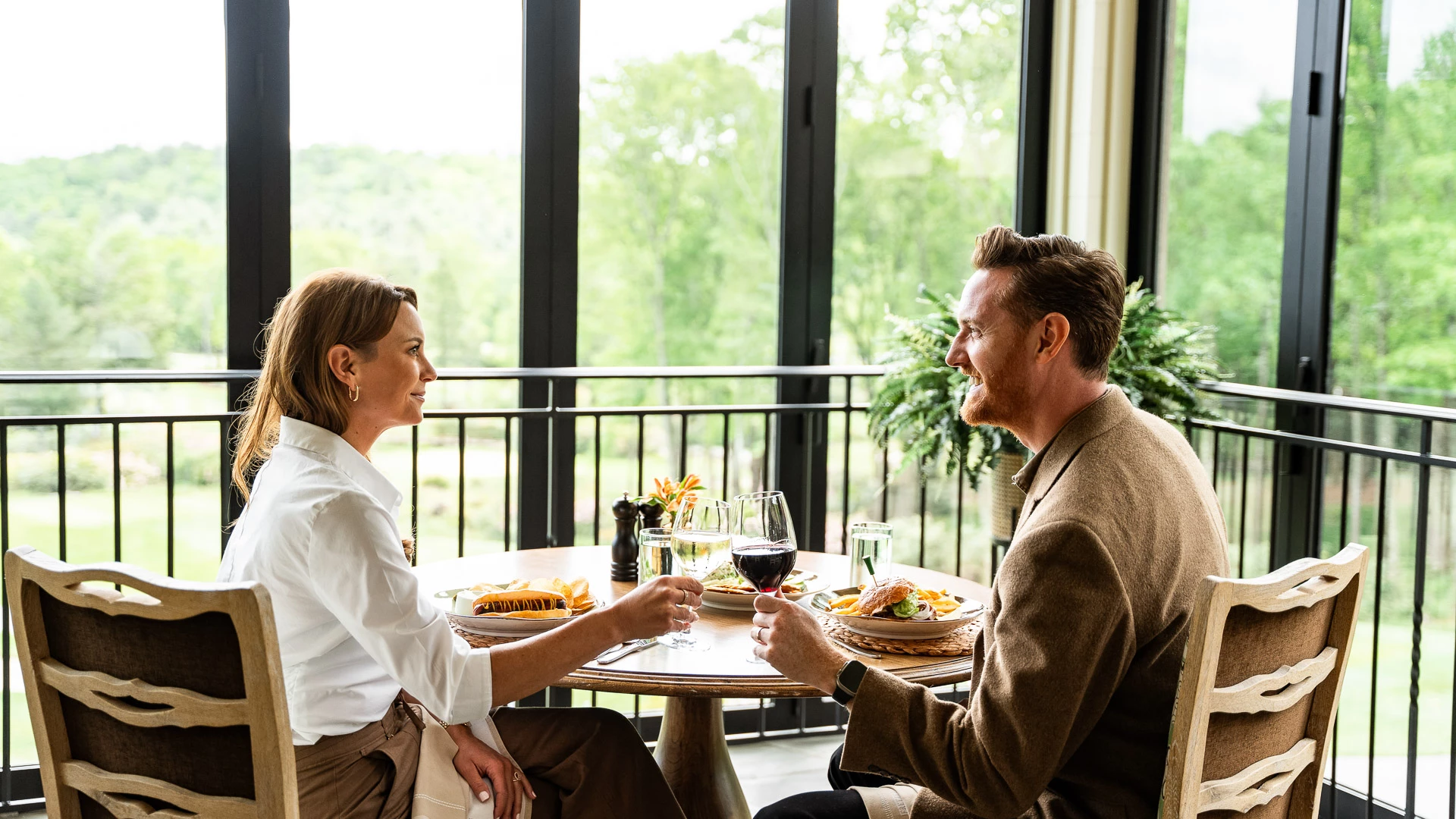 a man and woman sitting at a table with food and drinks