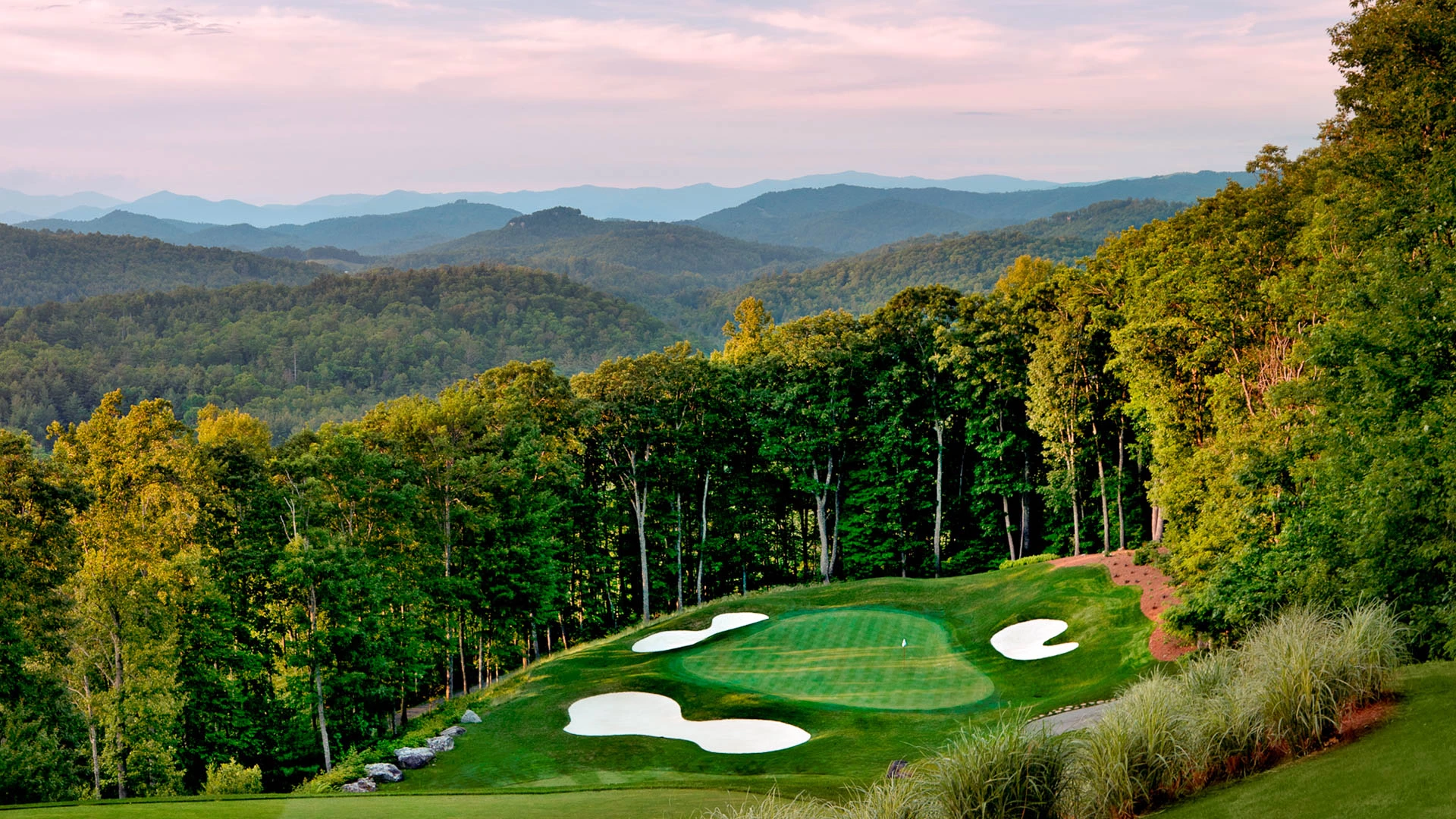 a golf course with trees and hills in the background