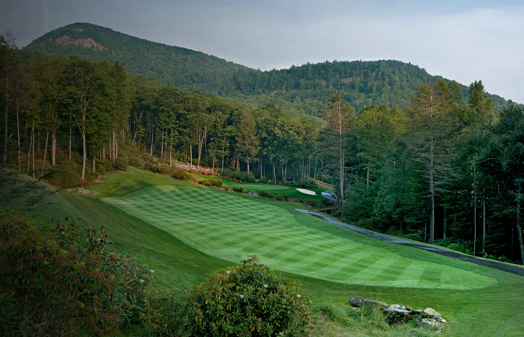 a golf course with trees and hills in the background