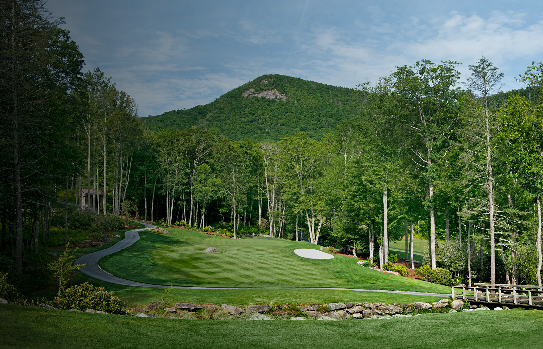 a golf course with trees and a hill in the background